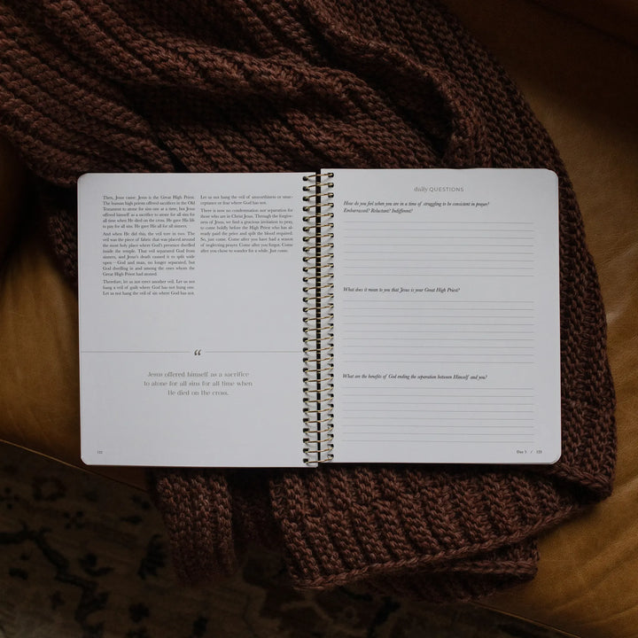 The Pray Spiral Study opened to the daily questions page on a woven blanket