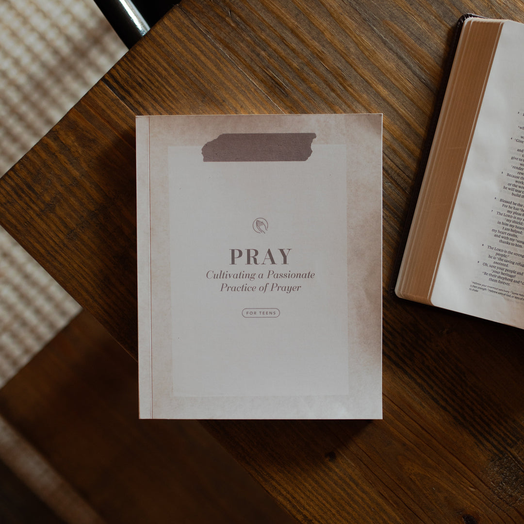 The Study called Pray cover on a wooden table near an open bible