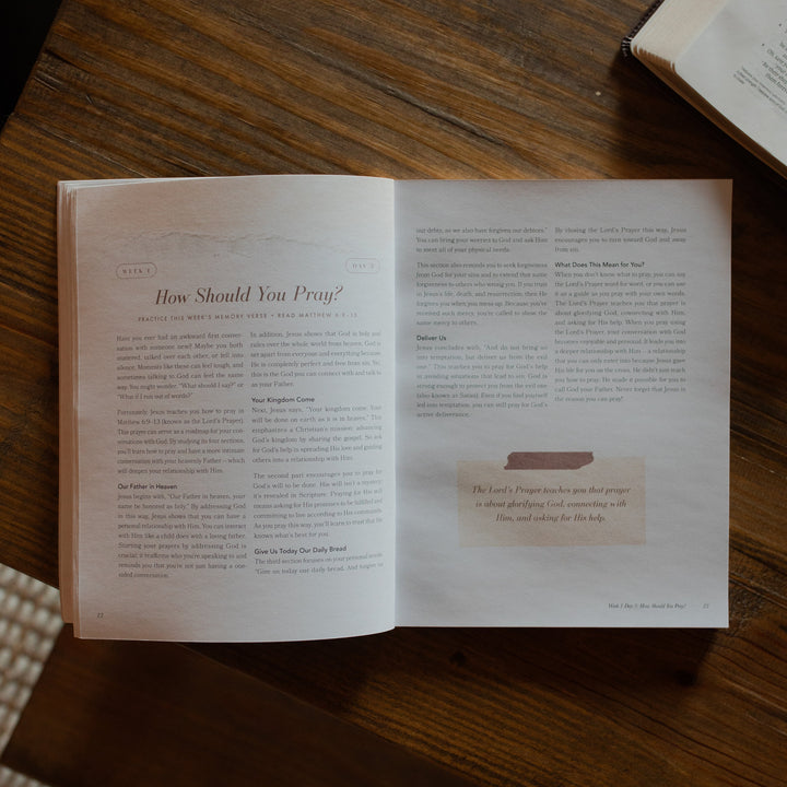 The Pray study opened to week 1 page the table of contents on a wooden table near an open bible
