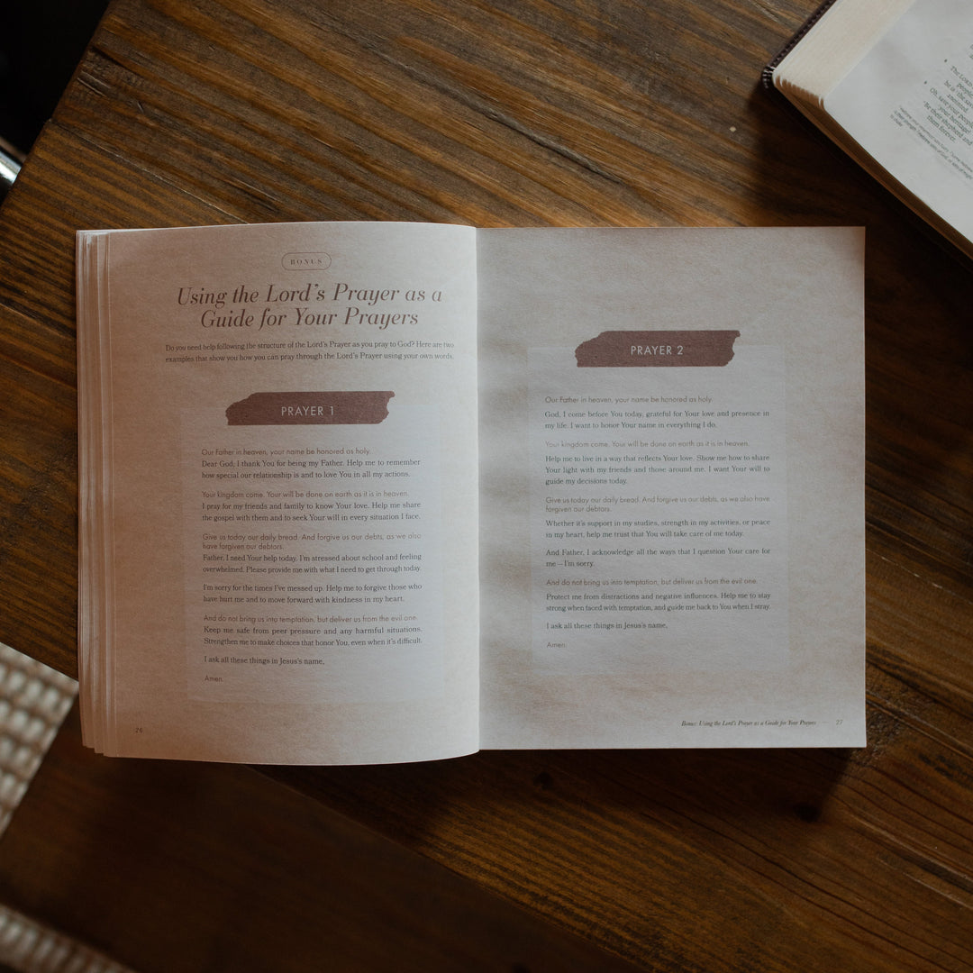The Pray study opened to the prayers page on a wooden table near an open bible