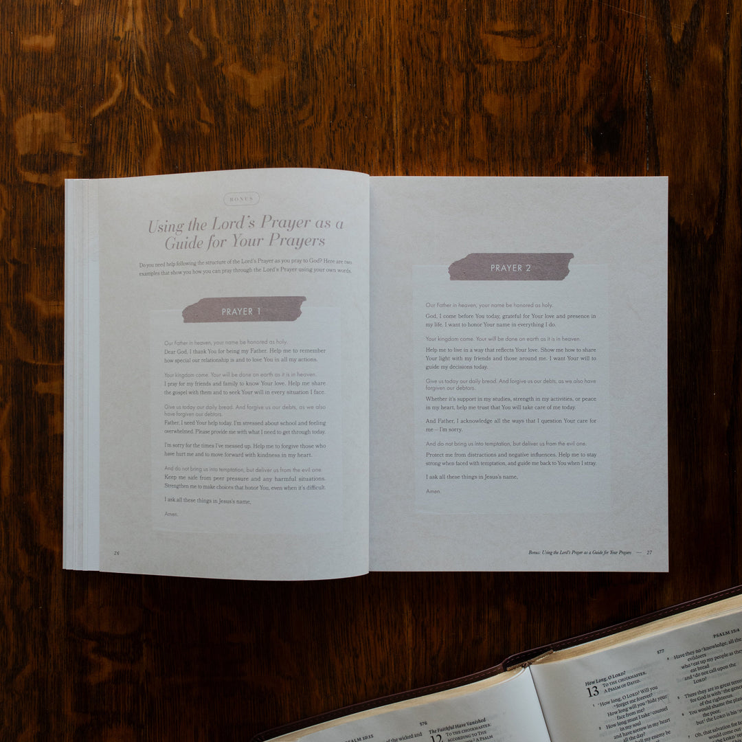 The Pray Study opened to the prayers page on a wooden table near an open bible