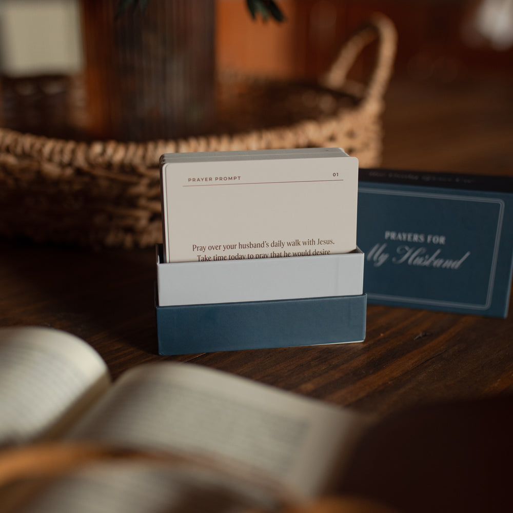 an open blue box with 'Prayers for My Husband' text on a wooden surface near a potted plant