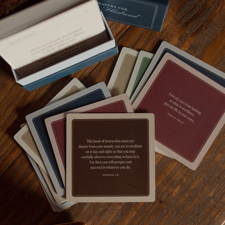 Multiple prayer cards with a blue box labeled 'The Daily Prayer' on a wooden surface.