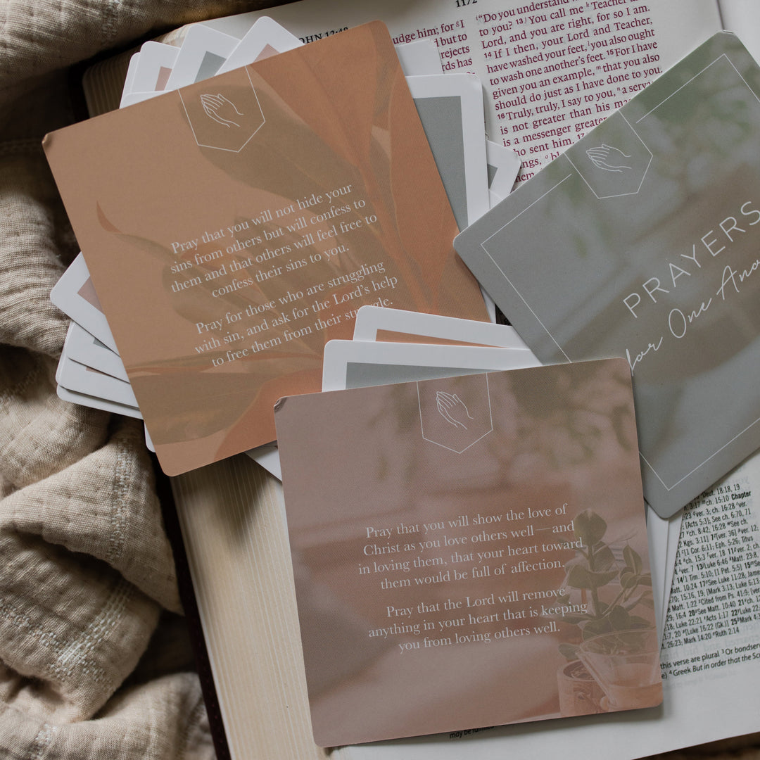 Backs of Multiple Prayers for One Another verse cards with rounded corners on an open bible