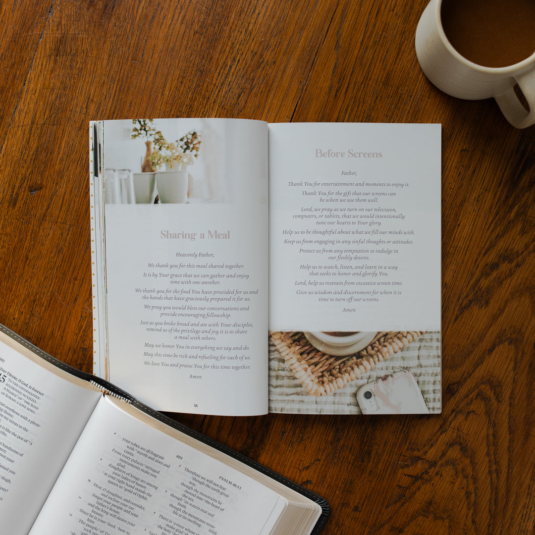 The Prayers for your Day opened to the sharing a meal page on a wooden table near a coffee cup