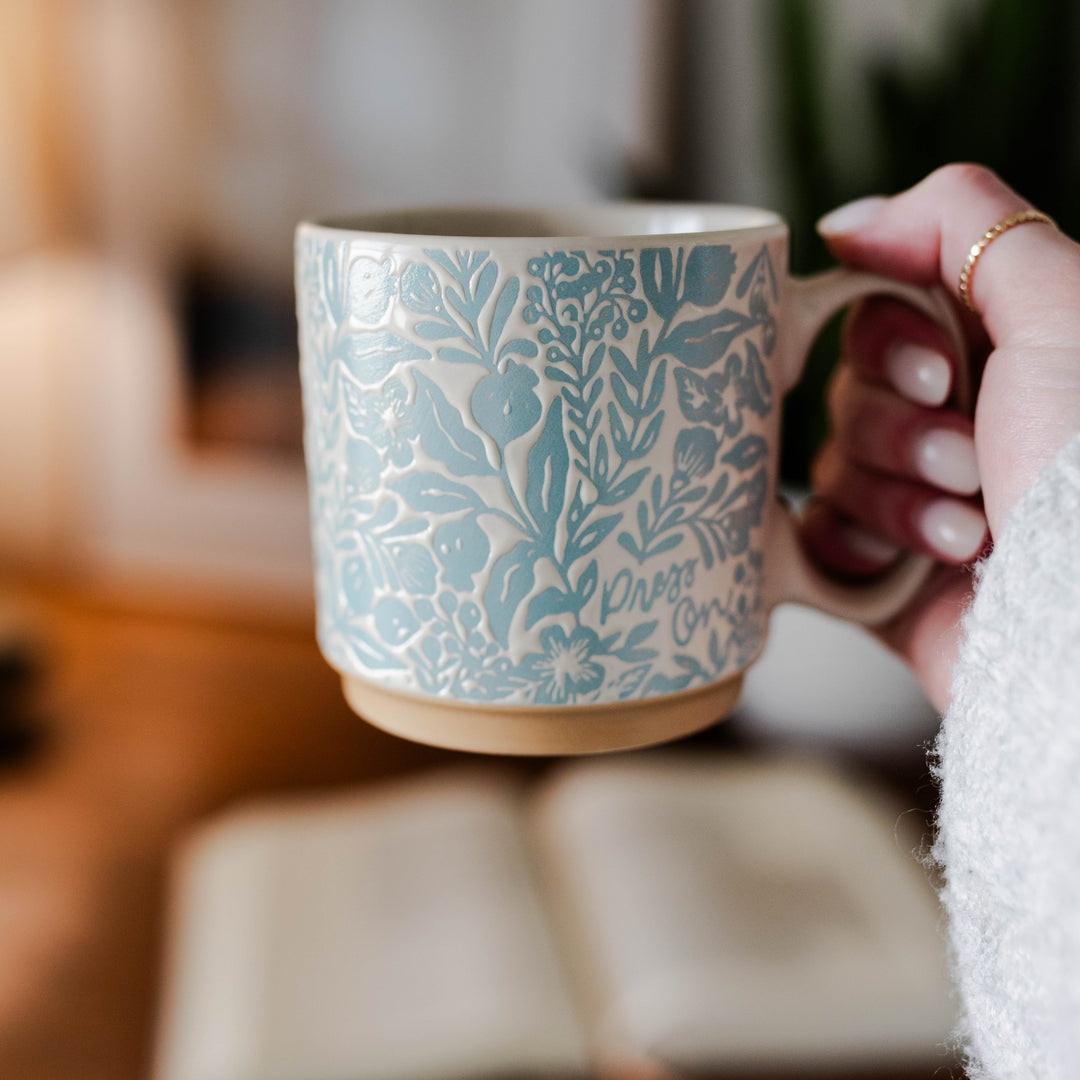 A blue and white mug with the words "press on"