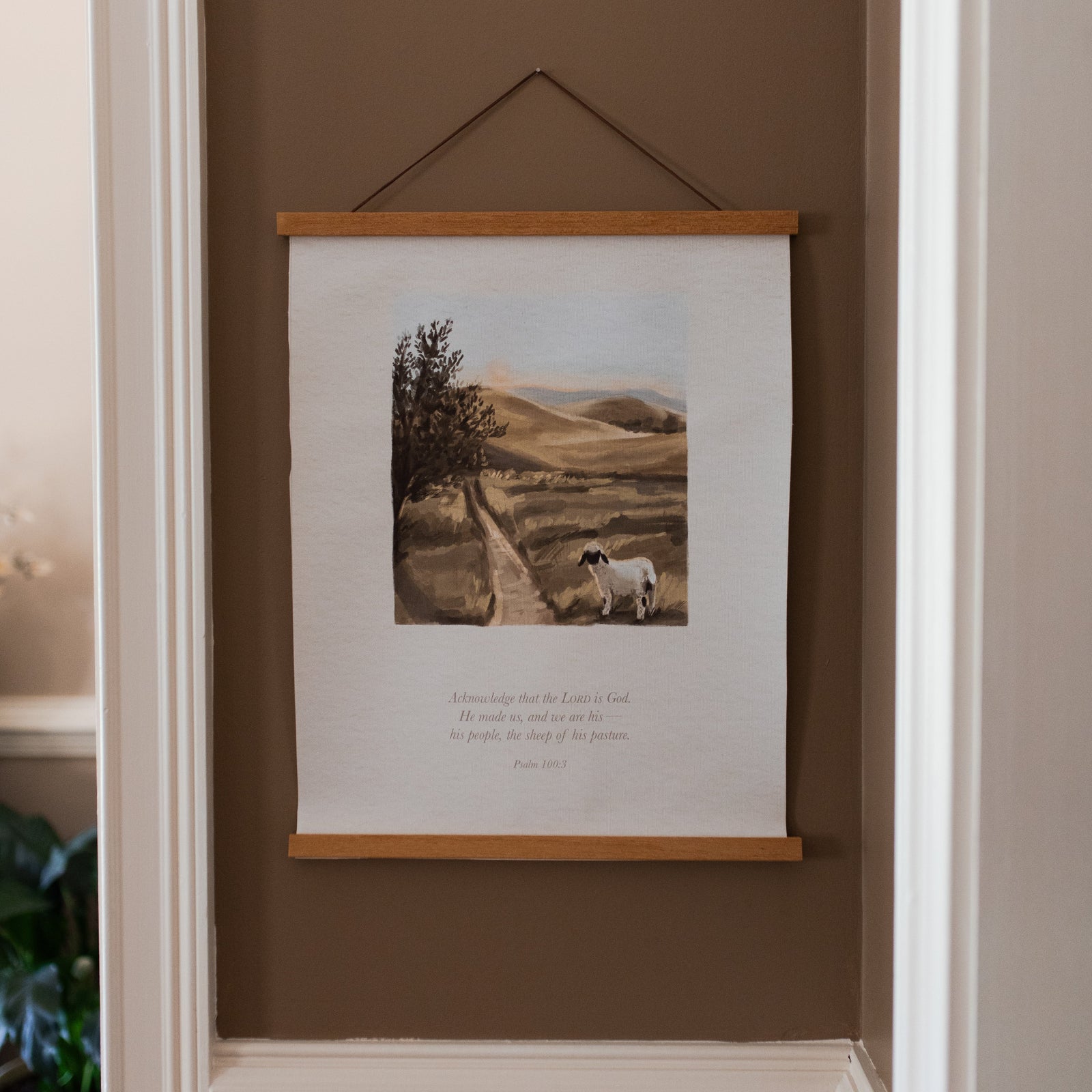 Sheep of his Pasture Canvas hanging on a brown wall with white trim