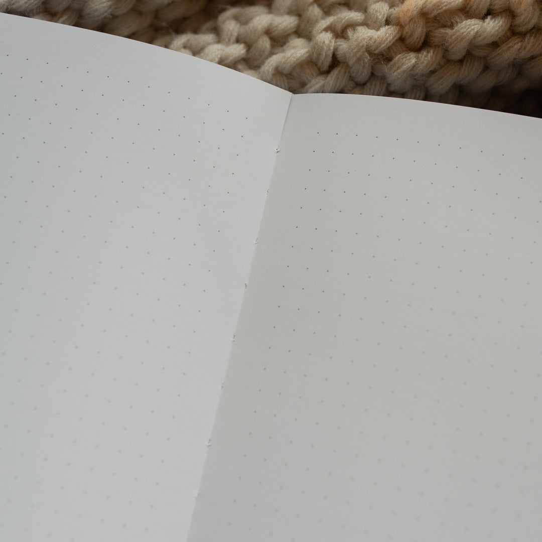Up close of The Psalm 121 Dotted Journal opened to a blank page on a white knitted blanket