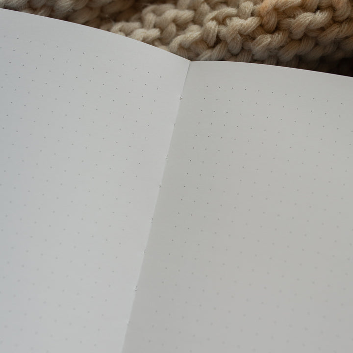 Up close of The Psalm 121 Dotted Journal opened to a blank page on a white knitted blanket