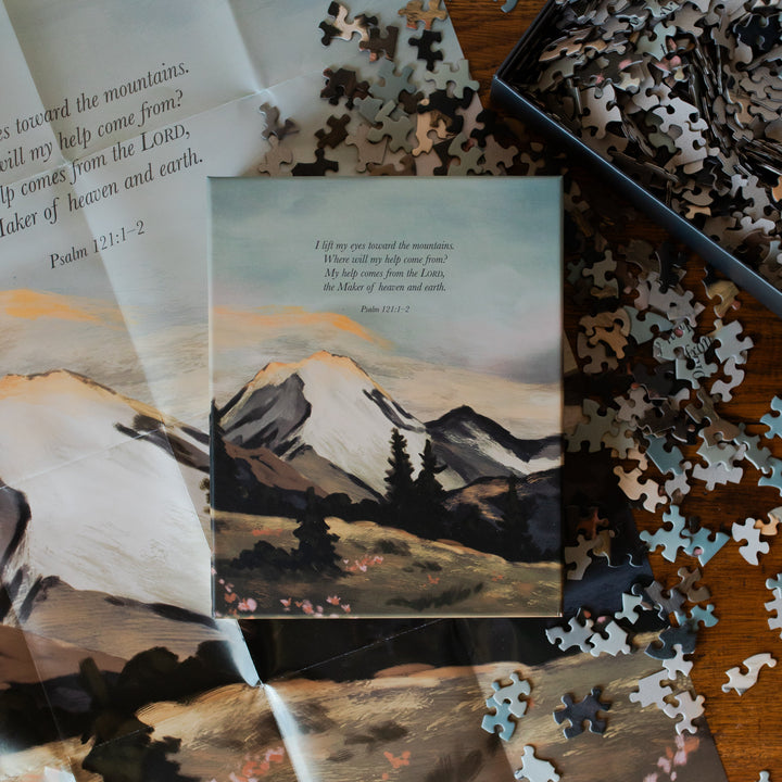 Psalm 121 Puzzle box laying on all of the puzzle pieces near the puzzle poster on the table