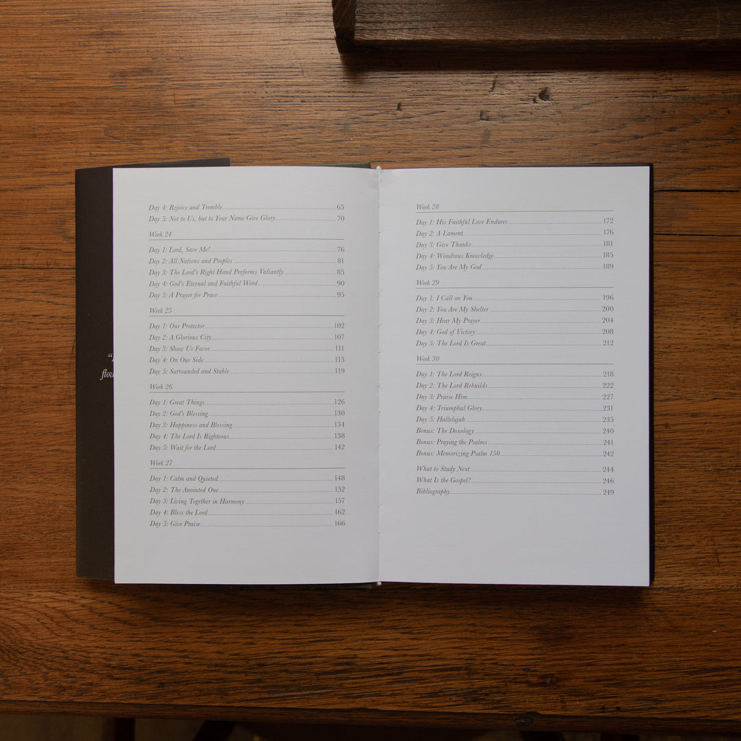 An open book displaying printed table-of-contents pages, placed on a dark wooden surface.