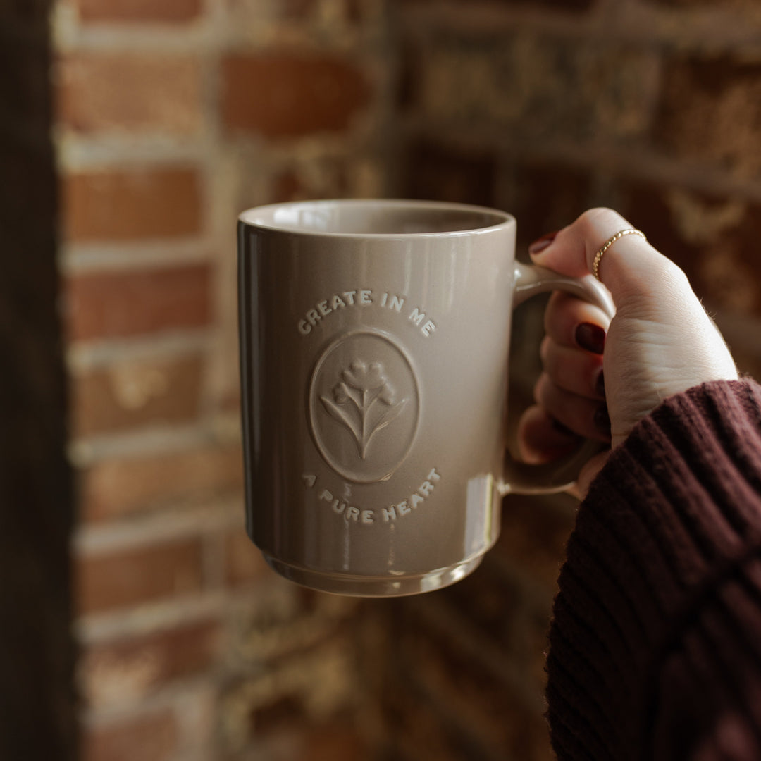 A woman holding a mug with the words Create In Me A Pure Heart