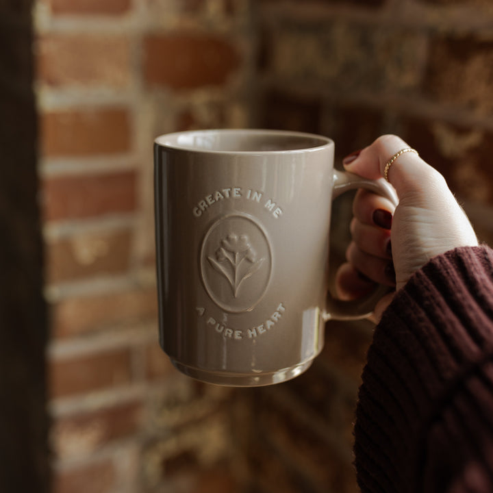 A woman holding a mug with the words Create In Me A Pure Heart