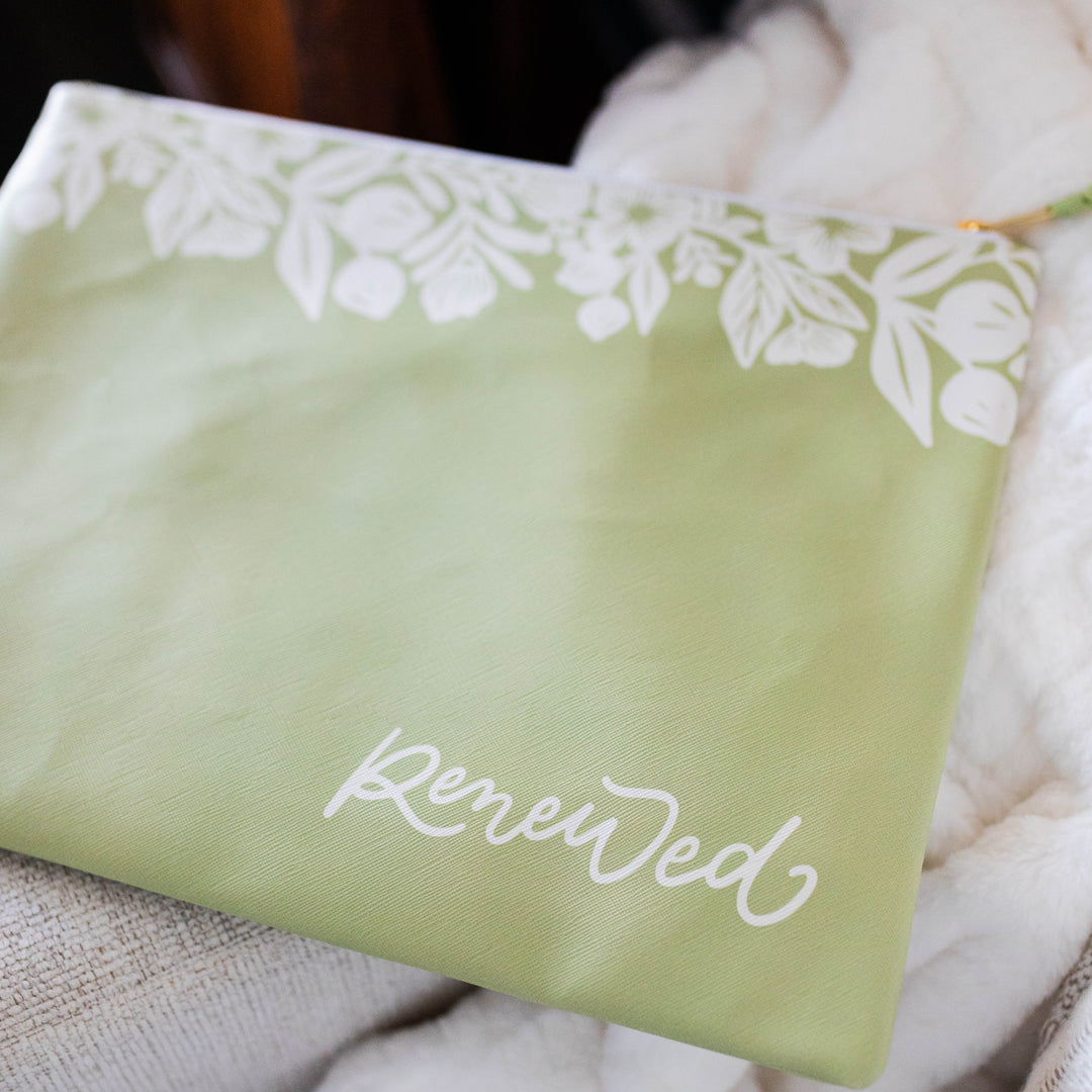 Green renewed pouch on a white couch. 