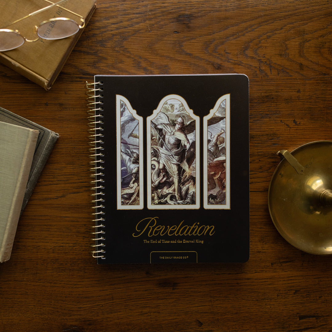 Revelation Spiral Study cover on a wooden table next to a bronze candlestick and some old books