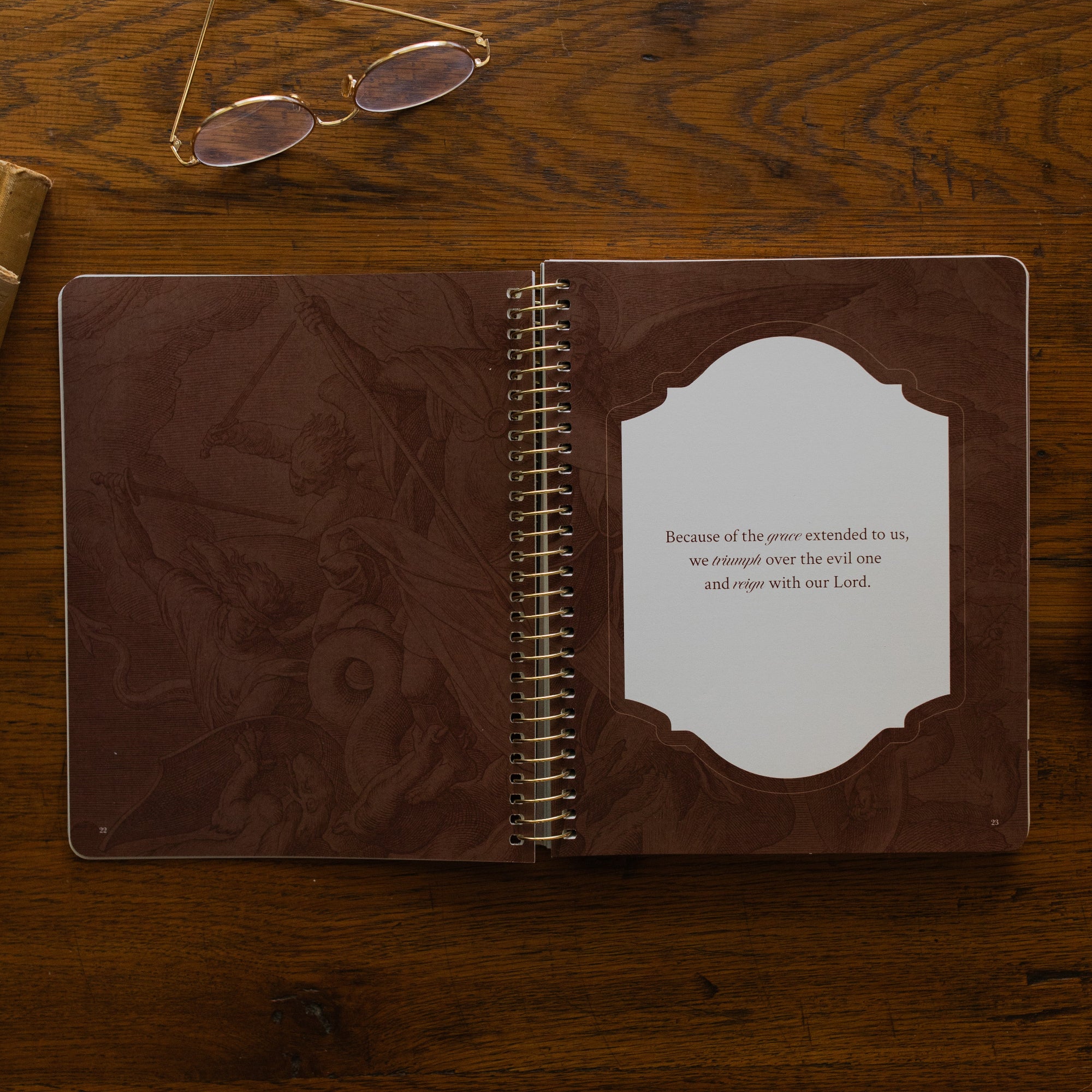 Revelation Spiral Study opened to page 23, a devotional quote, on a wooden table next to a pair of glasses