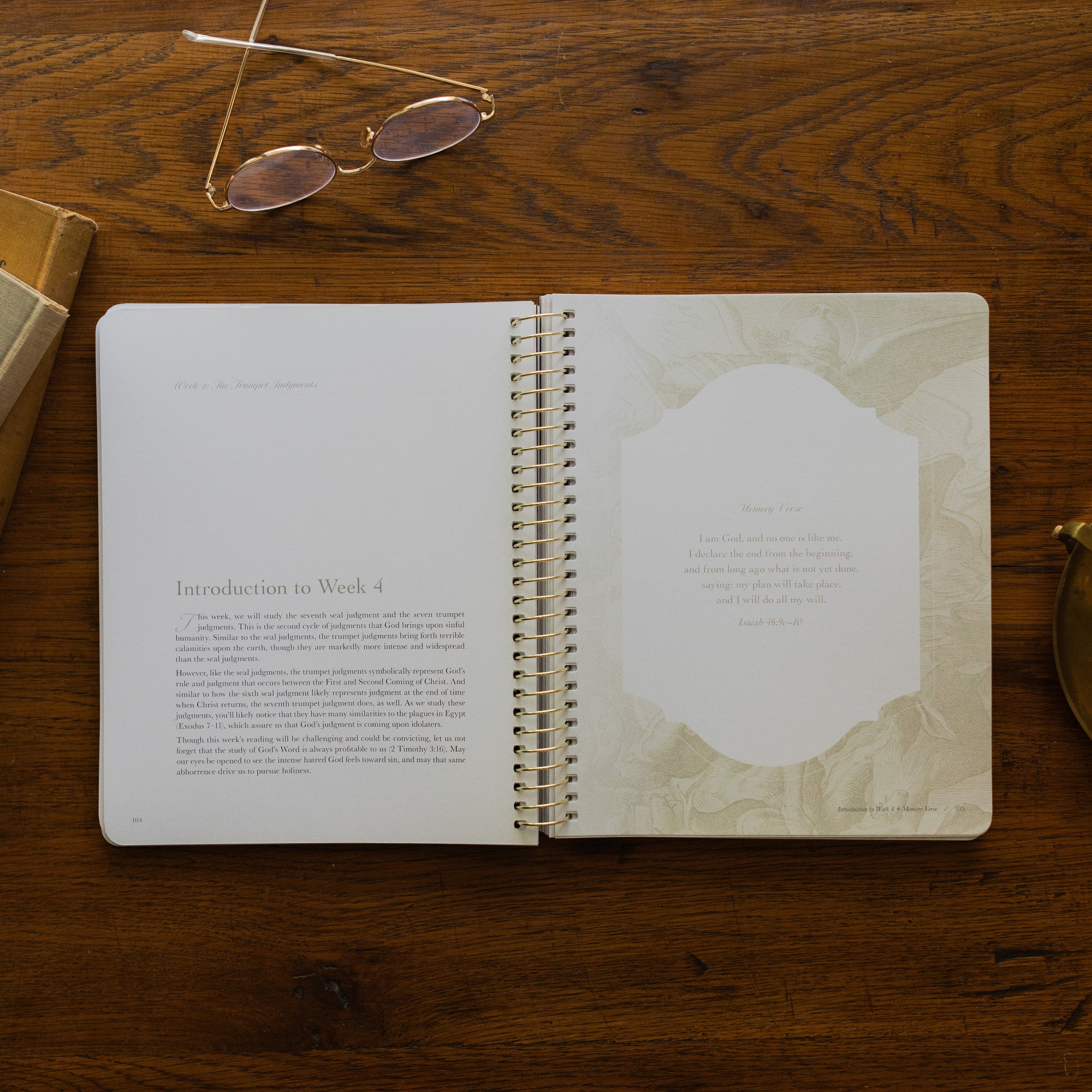 Revelation Spiral Study opened to page 104, introduction to Week 4, on a wooden table next to a pair of glasses
