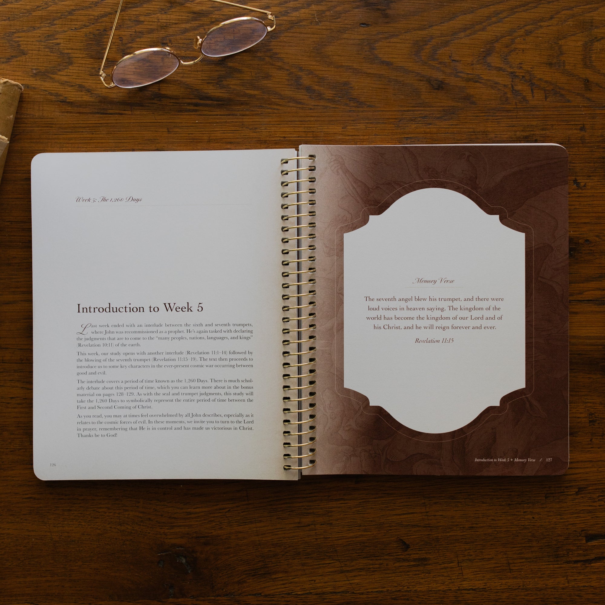 Revelation Spiral Study opened to page 126, introduction to week 5 and memory verse page, on a wooden table next to a pair of glasses