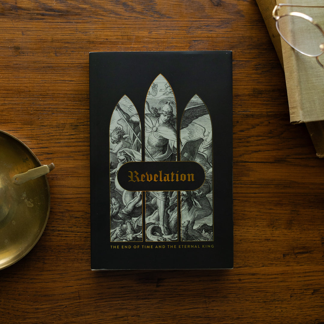 Revelation Hardcover on a wooden table next to a bronze candlestick and some old books