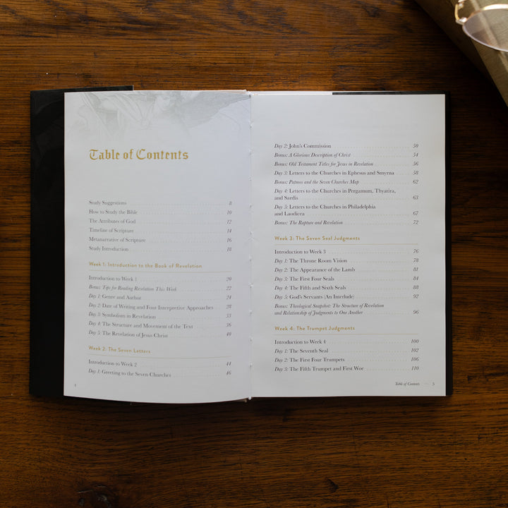 Revelation Hardcover opened to the Table of Contents page on a wooden table