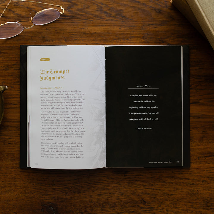 Revelation Hardcover opened to week 4 page, The Trumpet Judgments and a Memory Verse, on a wooden table next to a pair of glasses