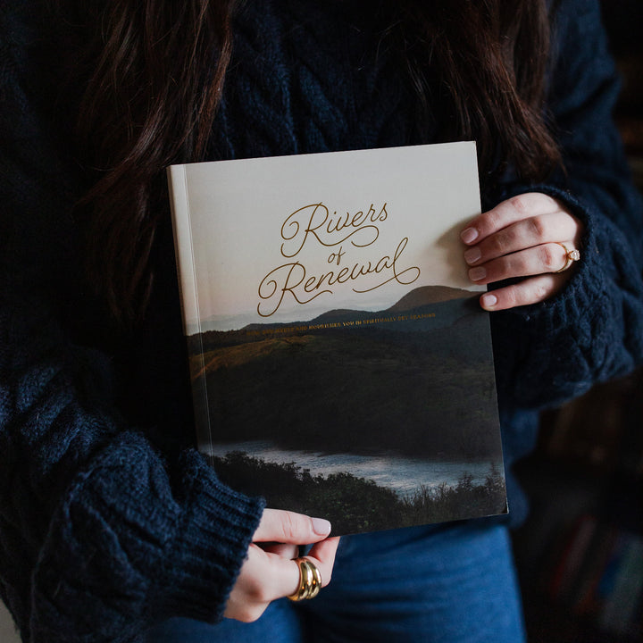 Rivers of Renewal Study being held by a woman with a blue long sleeve sweater and blue jeans