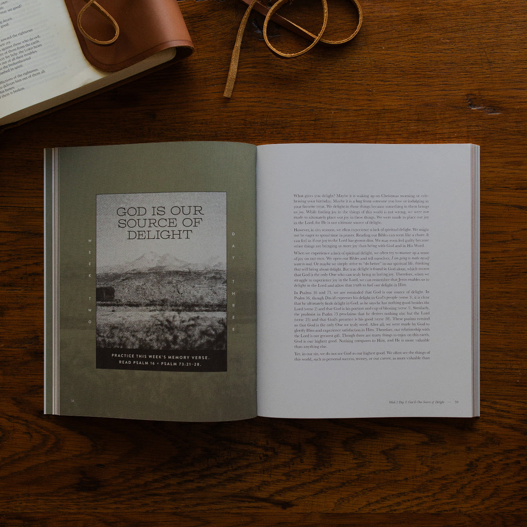 Rivers of Renewal Mens Study opened to week 2 day 3 page on a brown wooden table next to leather wrapped bible