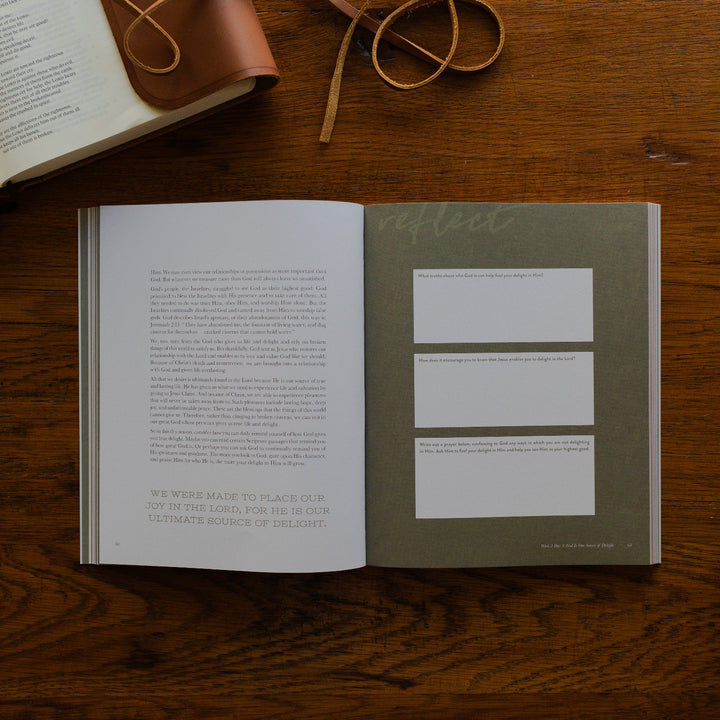 Rivers of Renewal Mens Study opened to the reflection page on a brown wooden table next to a leather wrapped bible