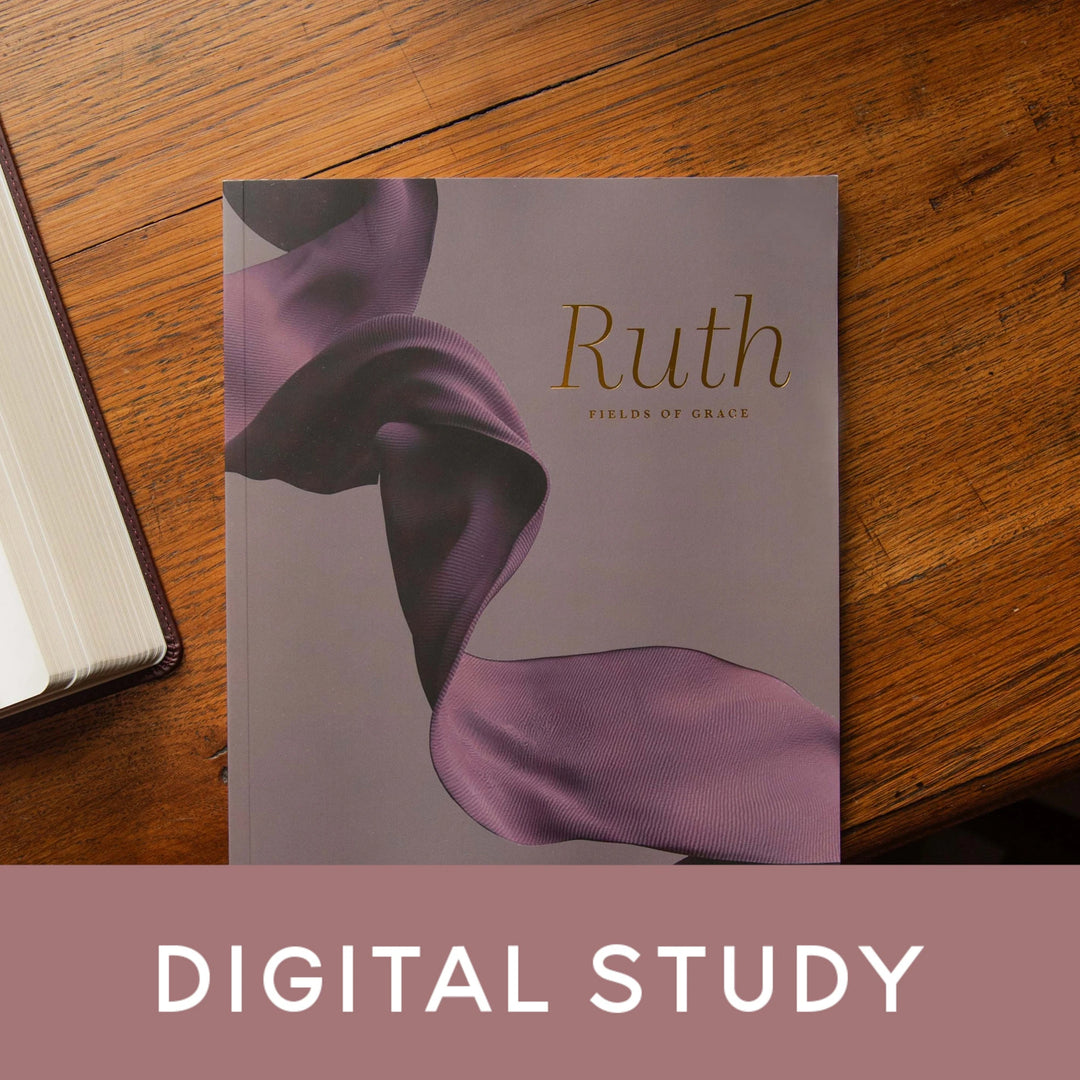 A book titled 'Ruth: Fields of Grace' by The The Daily Grace Co. lies on a warm wooden table. The visible cover features a flowing purple ribbon design on a muted lavender-gray background.