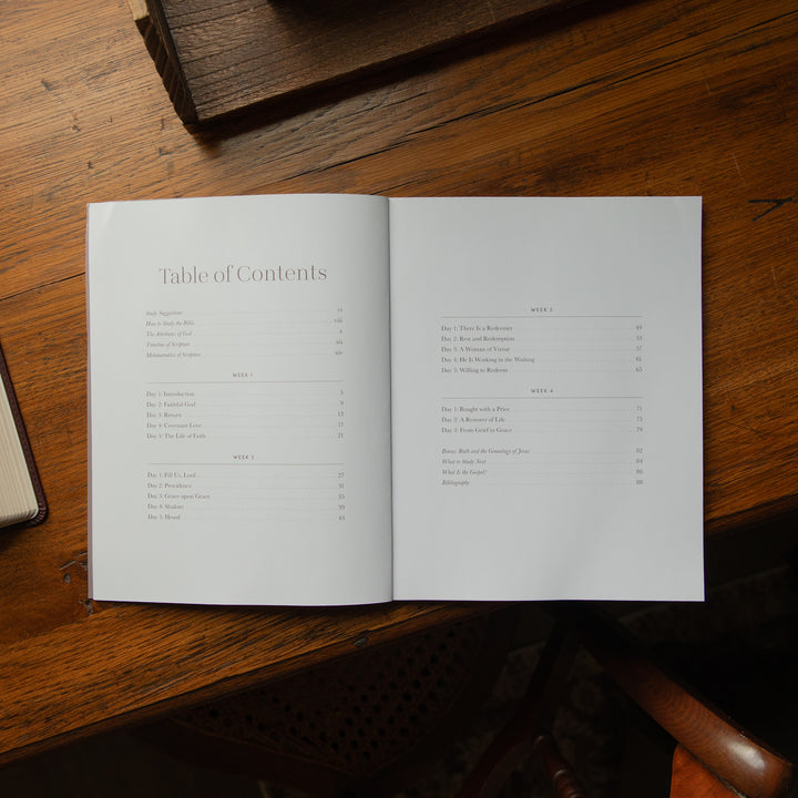 An open book showing the Table of Contents spread on a warm wooden table.