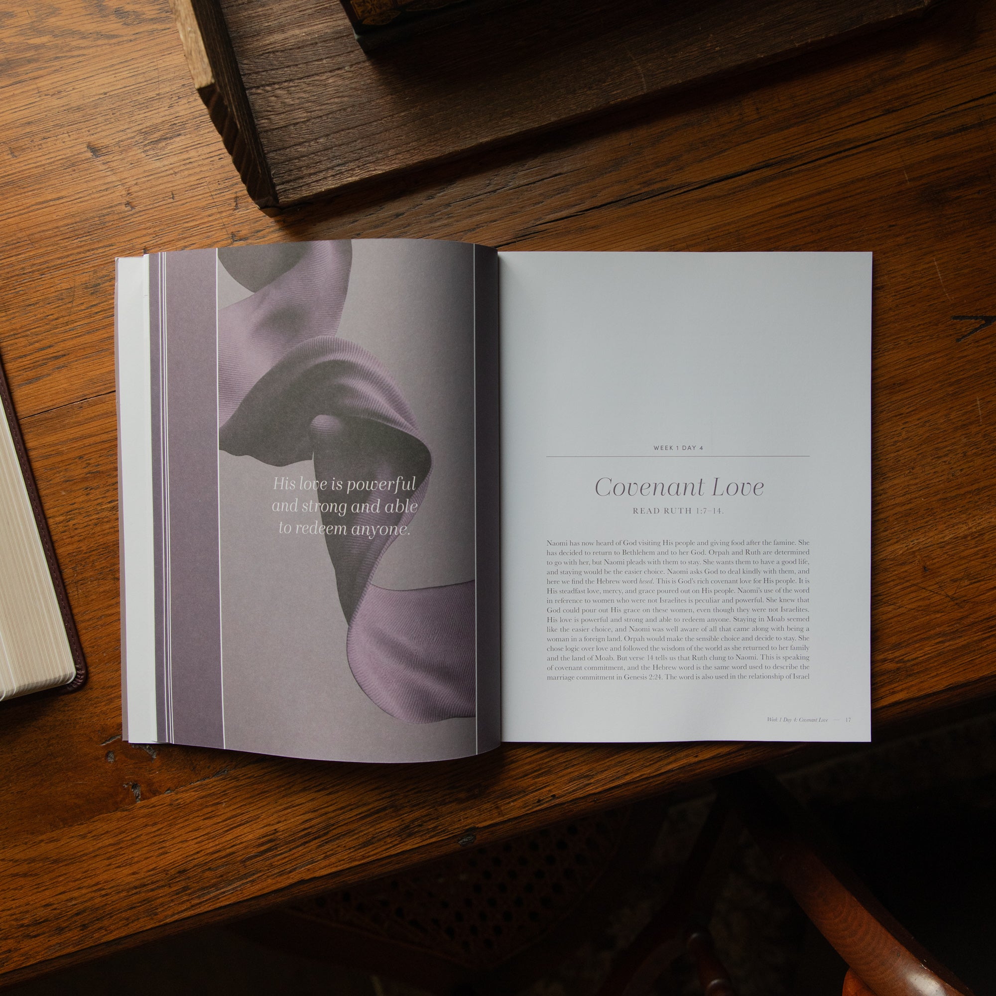An open book laid on a wooden table, showing a two-page spread with a muted purple abstract photograph on the left page and a text page titled 'Covenant Love' on the right. The scene is photographed from above in warm natural light.