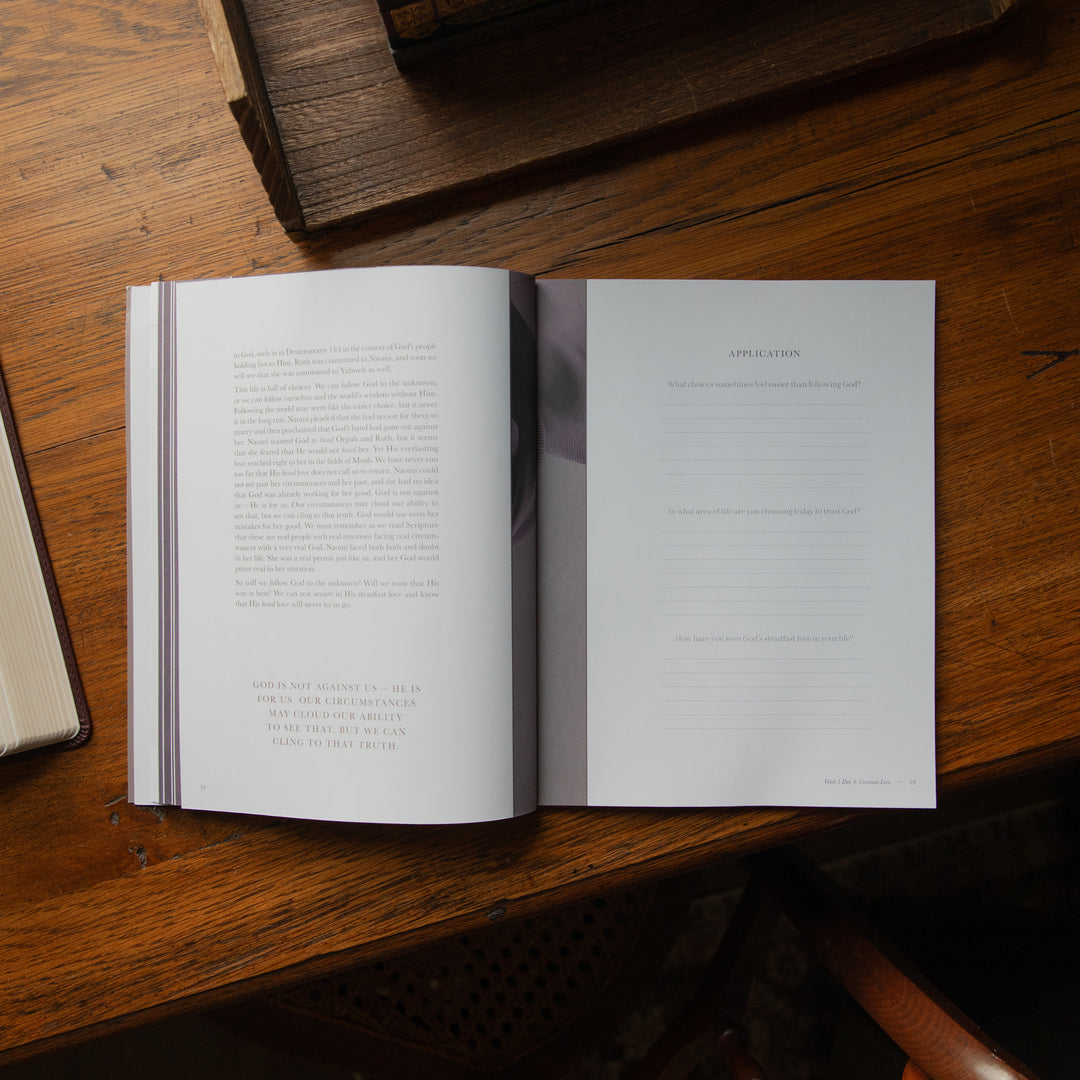 An open book laid on a wooden table, showing printed text on the left page and lined writing space on the right page.
