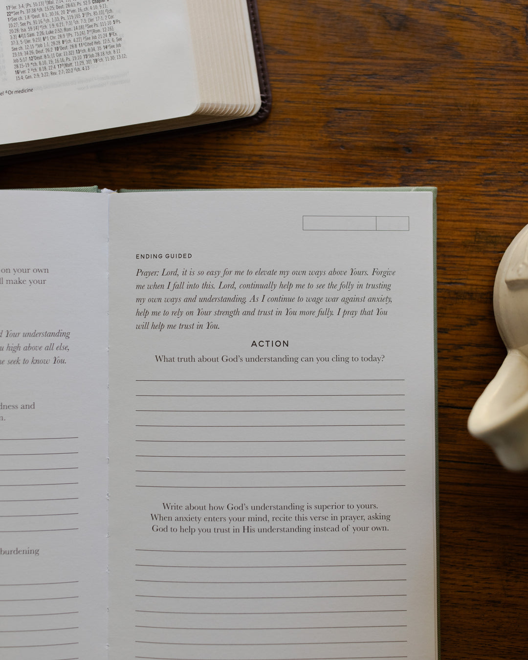 Open book on a wooden surface with a white object next to it