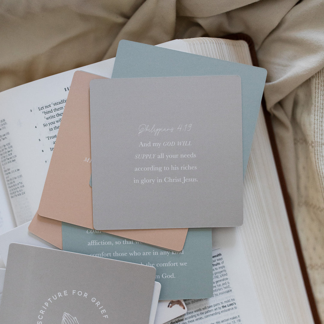 Example of a Scripture for Grief Verse Card laying on a open bible; The bible is resting on a light tan colored cloth