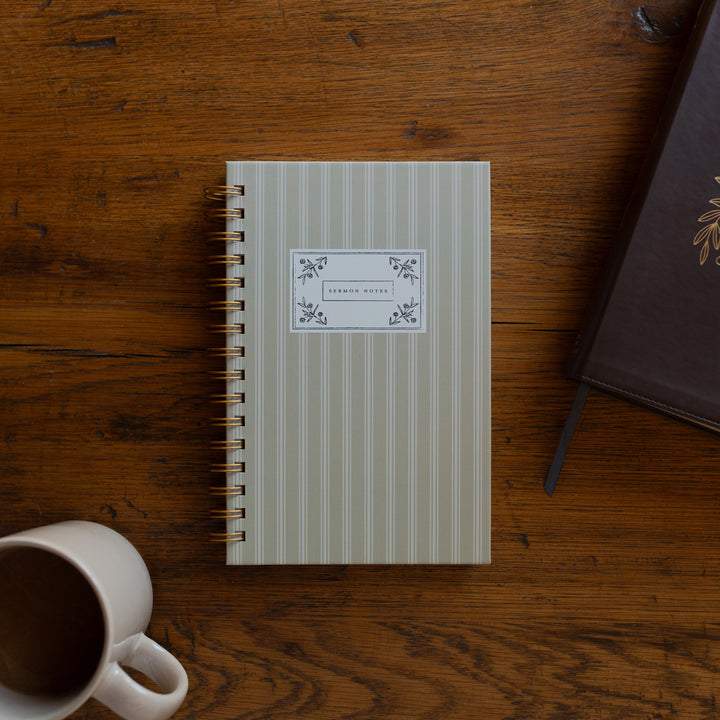 The Sermon Notes Journal with Pale Stripes next to a bible and a coffee cup on a wooden table