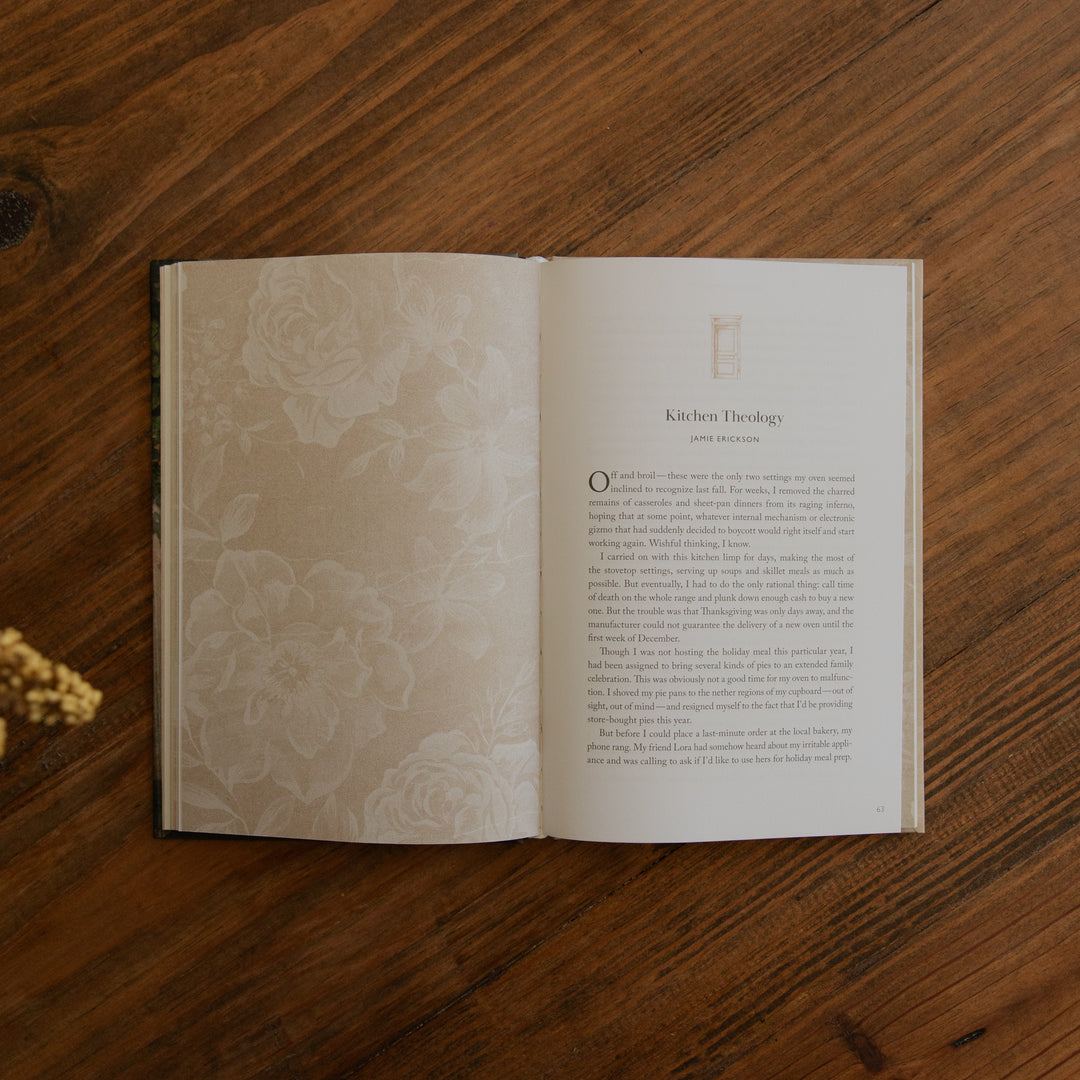 An open book with cream-colored pages featuring embossed floral patterns on the left page and printed text on the right, placed on a dark brown wooden surface.
