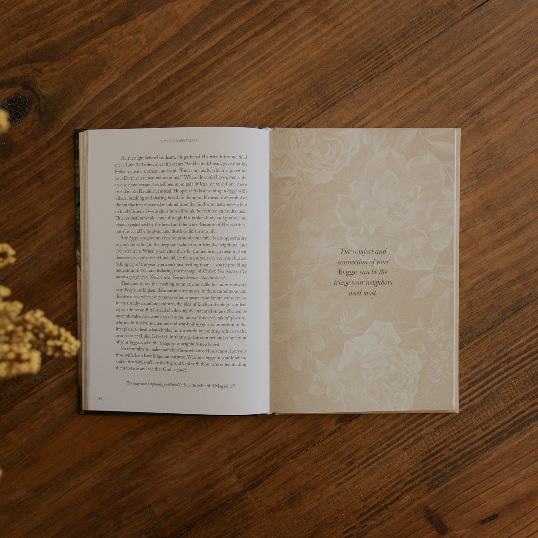 An open book with printed text on the left page and a decorative floral page on the right, placed on a wooden tabletop.