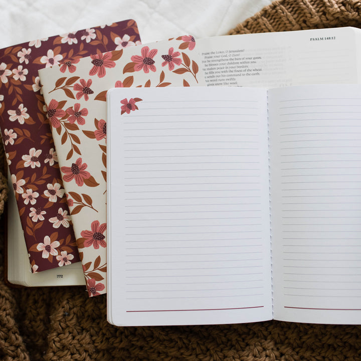 A set of three journals with floral prints showing inside of lined pages