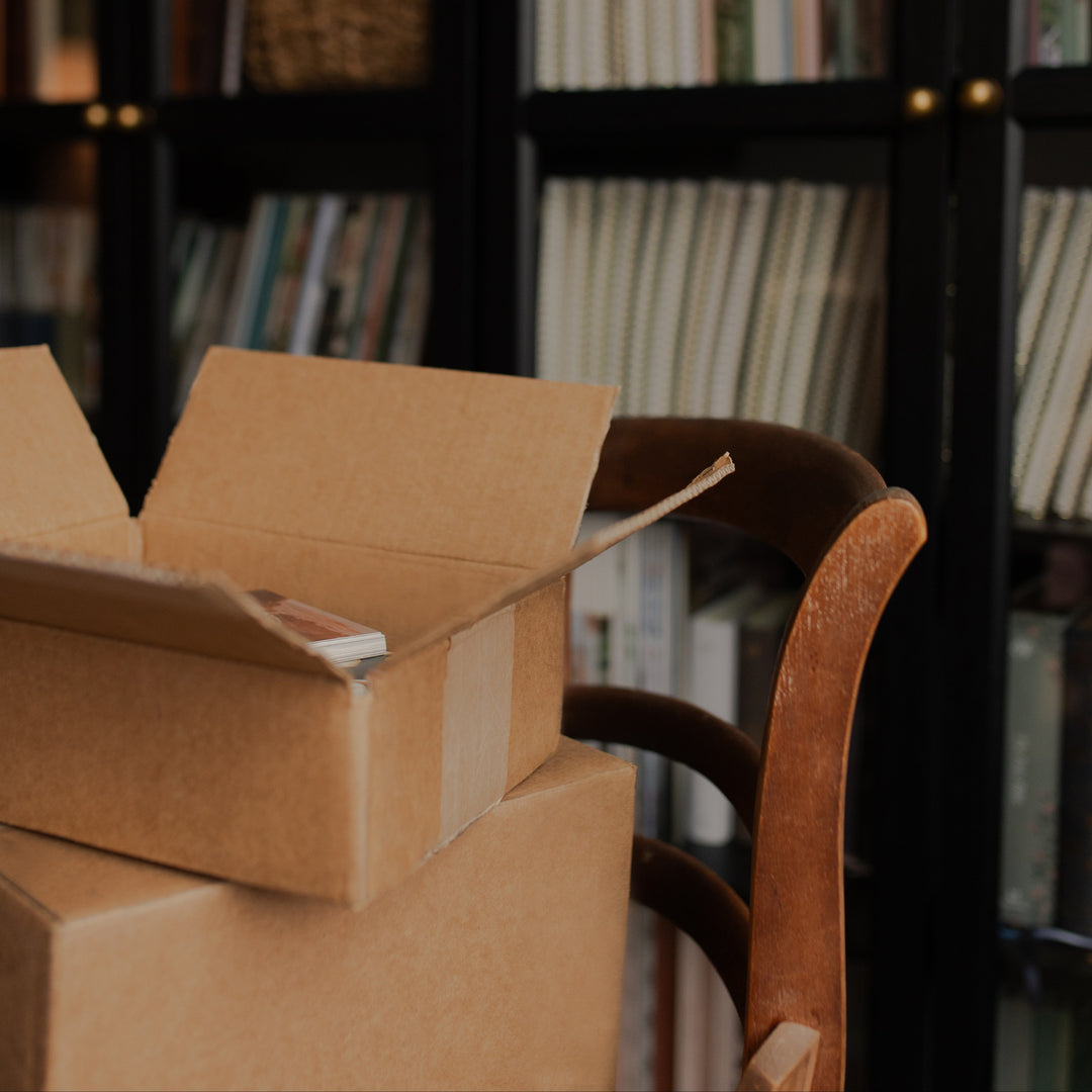Cardboard boxes in a room with bookshelves in the background