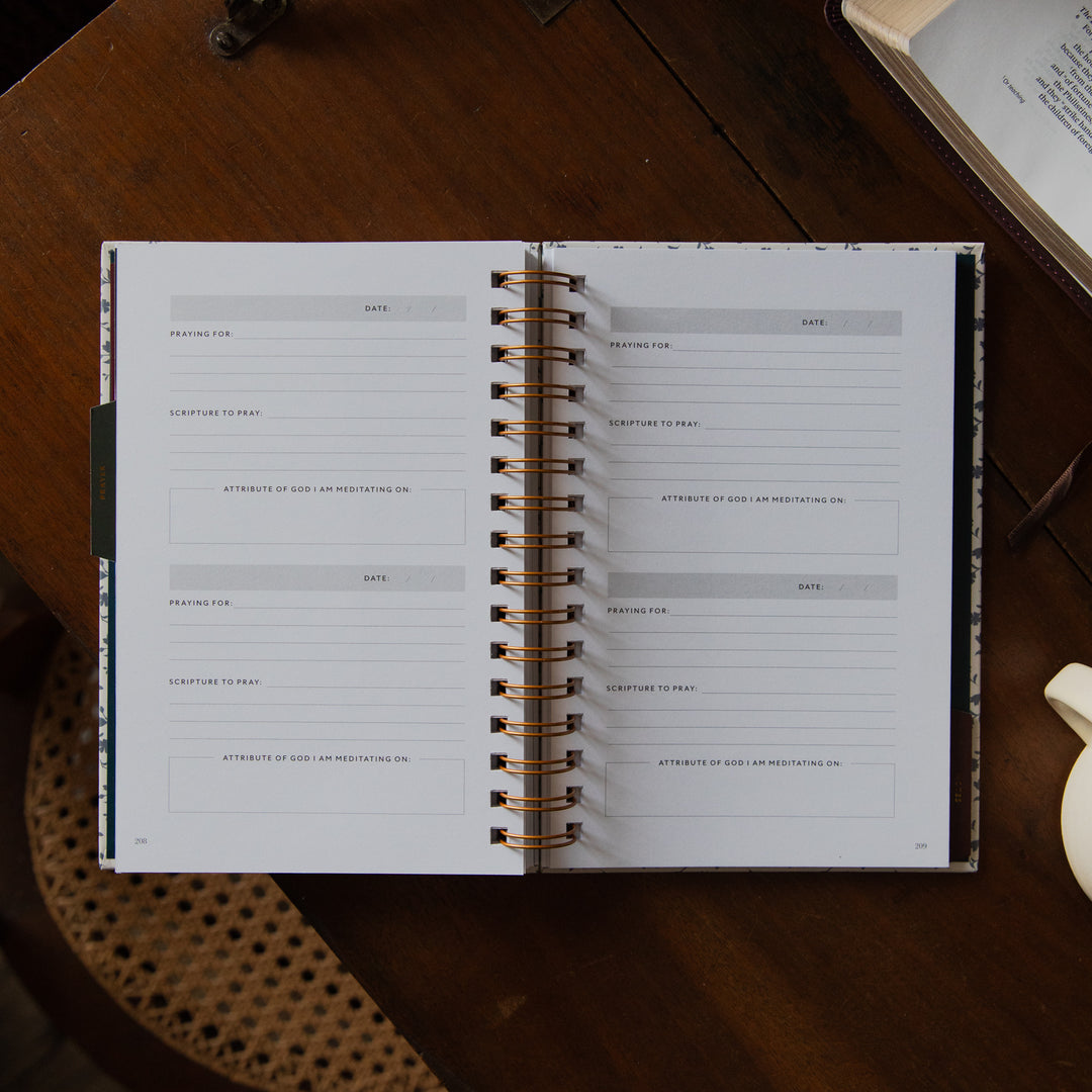 An open spiral-bound planner or journal with lined pages for writing, photographed from above on a dark wooden table.