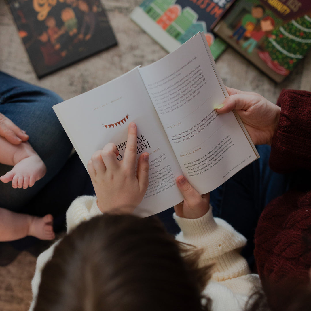 A woman and a child reading the Advent Adventure Devotional while the child is pointing to a page in the devotional