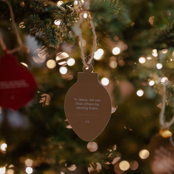 An ornament hanging that says In Jesus, We can love others by serving them