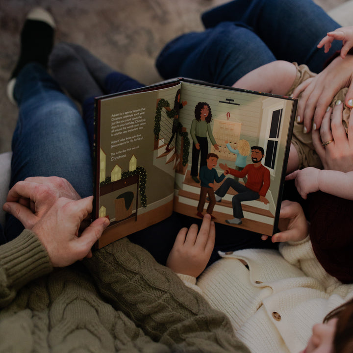 Multiple people sitting on a couch, looking at The Advent Gift together.
