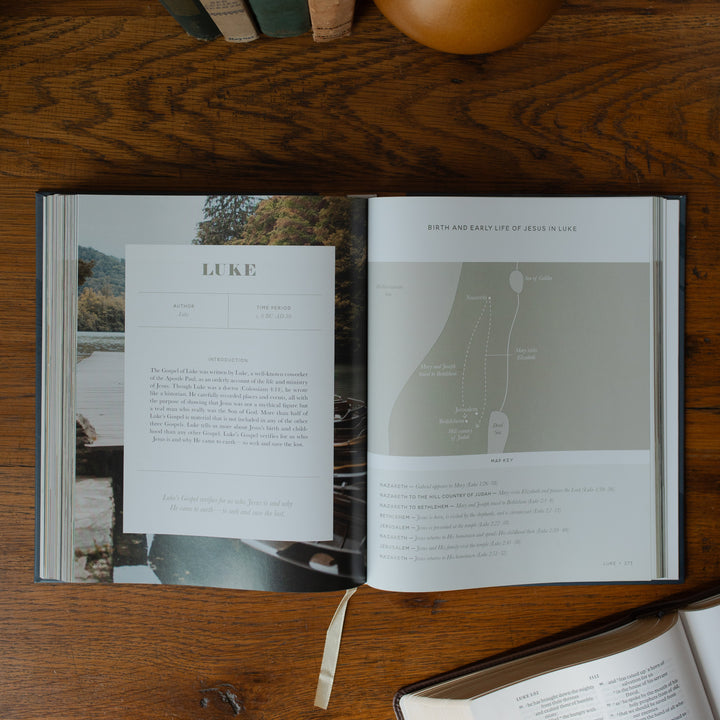 The Bible Maps Handbook opened to the Luke beginning page on a wooden table near an open bible