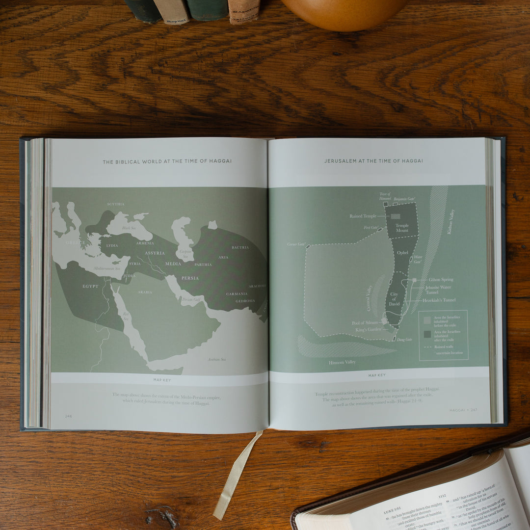 The Bible Maps Handbook opened to the Views at the time of Haggai page on a wooden table near an open bible