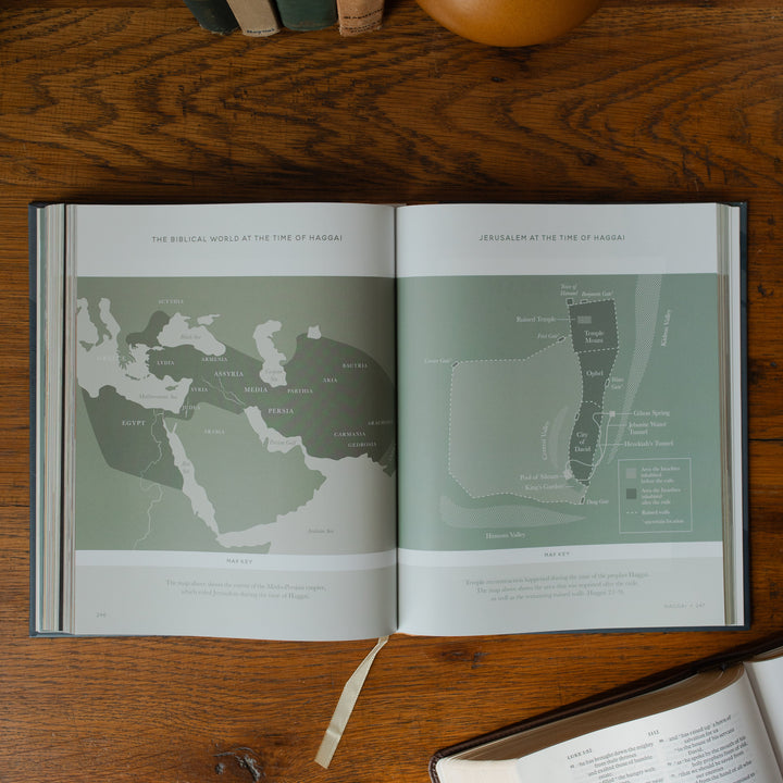 The Bible Maps Handbook opened to the Views at the time of Haggai page on a wooden table near an open bible