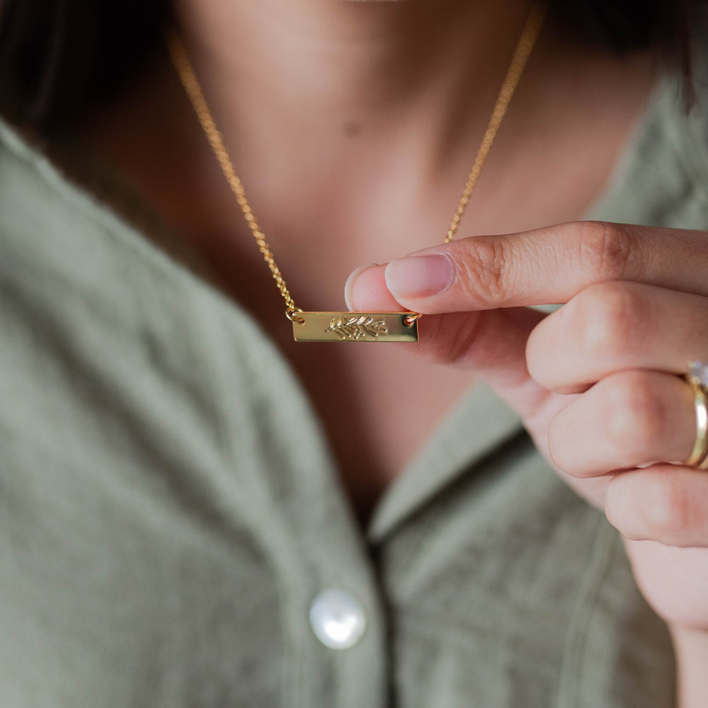 woman holding necklace bar to show design