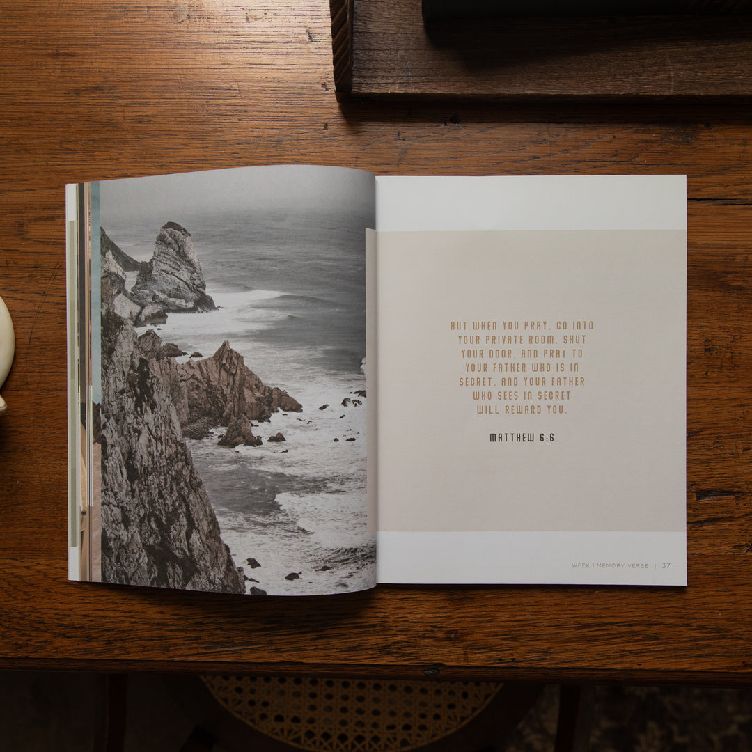 An open book lying on a wooden table, showing a black-and-white coastal cliff photograph on the left page and a beige text page on the right with a Bible verse from Matthew 7:6. No person or animal is present, so this is Product/Packaging rather than Lifestyle.
