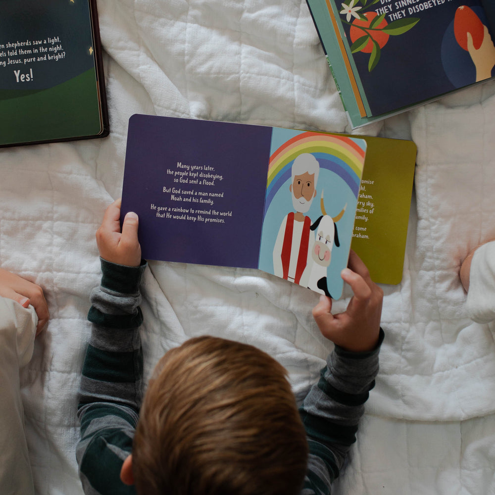 Little boy reading Christmas board book for kids called The Promised One