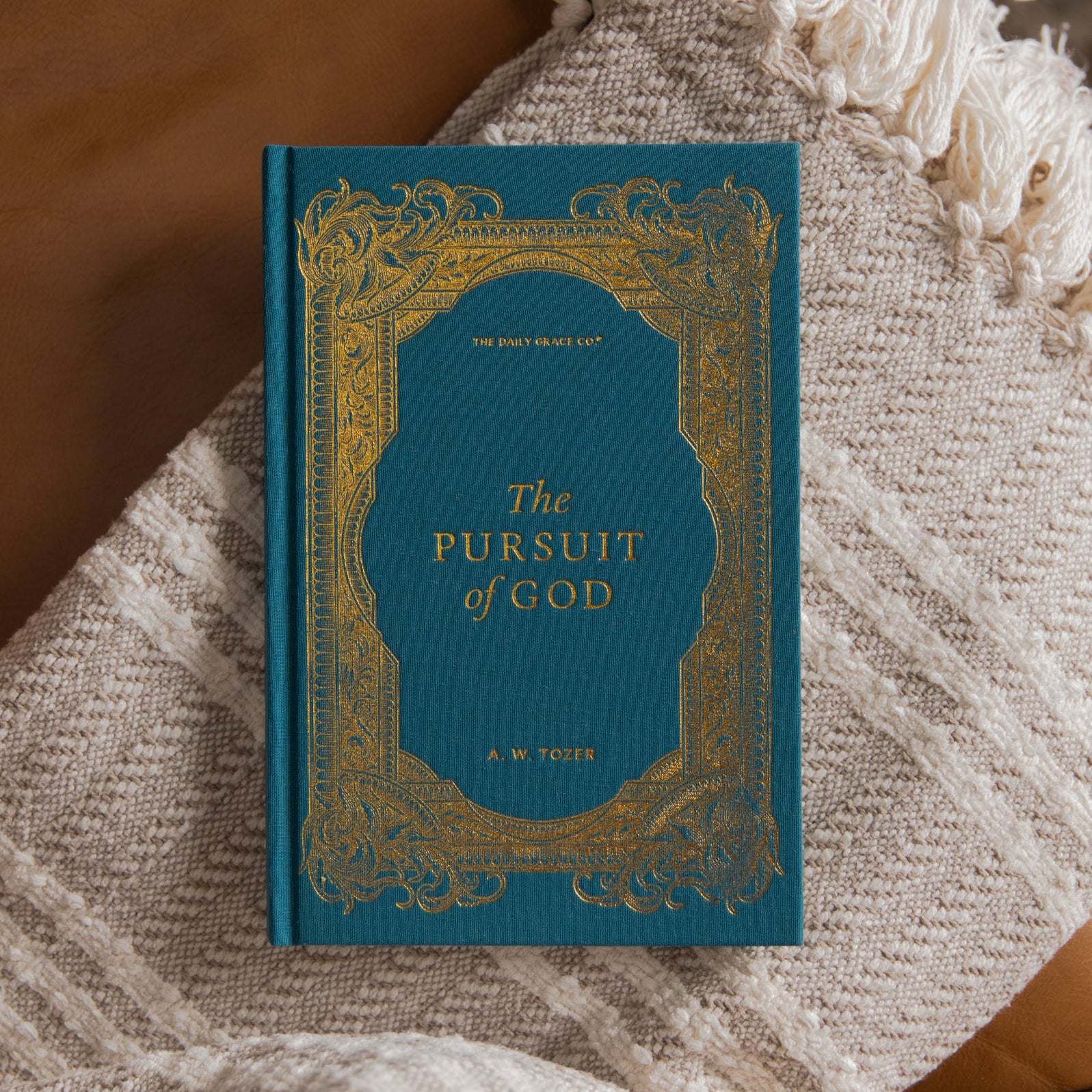 The Pursuit of God cover on a cream blanket and leather couch